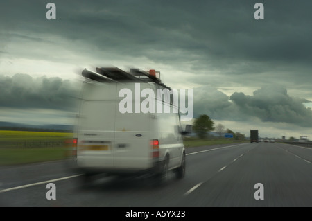 WEIßER LIEFERWAGEN MIT GESCHWINDIGKEIT ENTLANG DER AUTOBAHN IN RICHTUNG GEWITTERHIMMEL Stockfoto