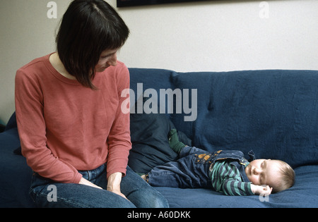 Mutter Uhren sieben Monate alte Tochter schläft neben ihr auf der couch Stockfoto