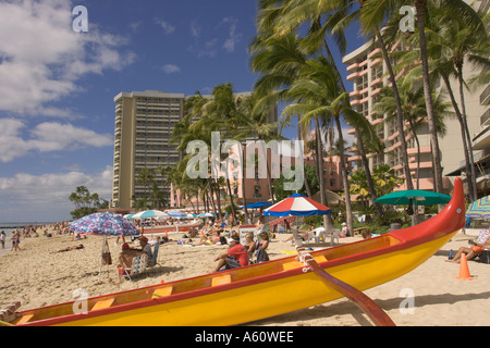 Blick entlang der Waikiki Beach Rot & gelber Ausleger-Kanu am Strand, blauer Himmel mit weißen Wolken Oahu Honolulu Hawaii hochgezogen Stockfoto