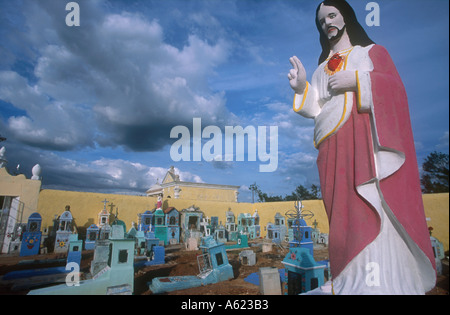 Mexiko Yucatan Hoctun Friedhof mit bemalten religiöse Statue von Jesus Christus im Vordergrund und Gräber gemalt, blau und Türkis Stockfoto