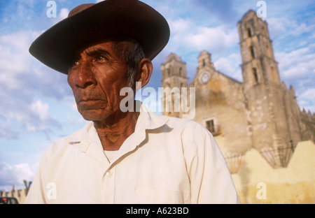 Mexiko Yucatan Hoctun älteren Mann tragen Hut Kopf und Schultern Porträt mit Kirchengebäude, die teilweise im Hintergrund gesehen Stockfoto