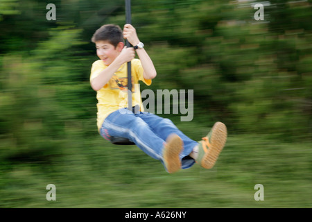 ein kleiner Junge reitet eine Spielzeug-Seilbahn Stockfoto