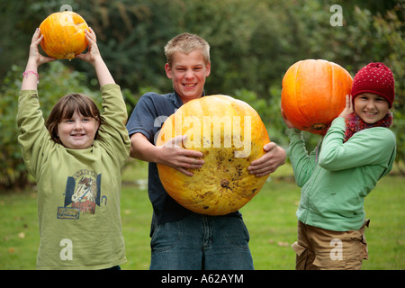 Porträt von drei glückliche Kinder heben Kürbisse für Spaß Stockfoto