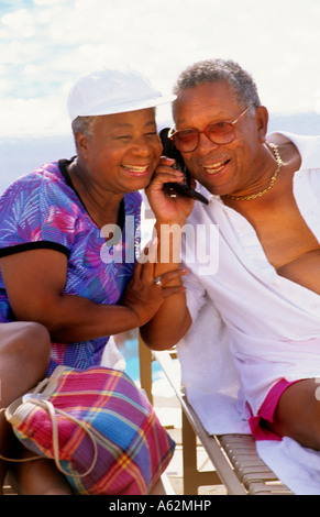 Attraktive und unterhaltsame schwarze Afro-Amerikaner im Ruhestand paar Zypressenreihen am Pool auf Handy zu Verwandten zu Hause anrufen Stockfoto