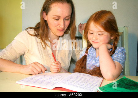 eine Mutter ihr Kind sitzt und schaut ihre Hausaufgaben Stockfoto