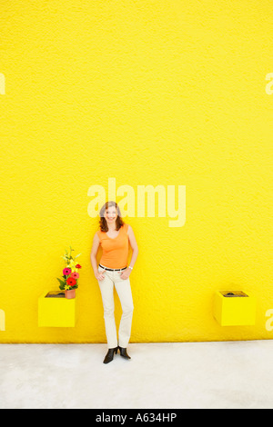 Reife Frau an eine Wand gelehnt und lächelnd Stockfoto