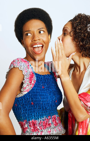 Reife Frau, eine junge Frau Ohr flüstern Stockfoto