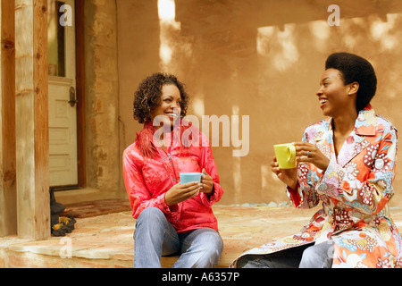 Junge Frau und eine reife Frau Kaffeetassen halten und Lächeln Stockfoto