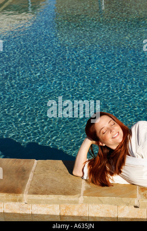 Vogelperspektive Blick auf eine reife Frau mit Augen geschlossen am Pool liegend Stockfoto