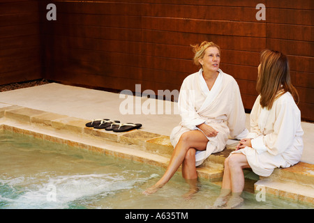 MIDI-Erwachsene Frau mit einer reifen Frau sitzt auf der Kante eines Whirlpools Stockfoto