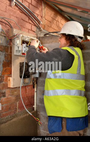 EINE ELEKTRIKER ENTFERNT ALTE STROM SICHERUNG BOXEN UND INSTALLIERT EINE MEMERA CONSUMER UNIT UK Stockfoto