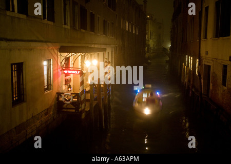 Ein Polizeiboot blau leuchtet blinkende Reisen an einem Kanal entlang vorbei an im Hotel Metropole in einer nebligen Nacht in Venedig Stockfoto