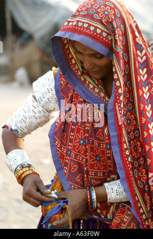Fleißige MIR nomadischen Tribeswoman Gujarat, traditionellen Schmuck tragen und helle farbige Kleidung mit Schleier über dem Kopf Stockfoto