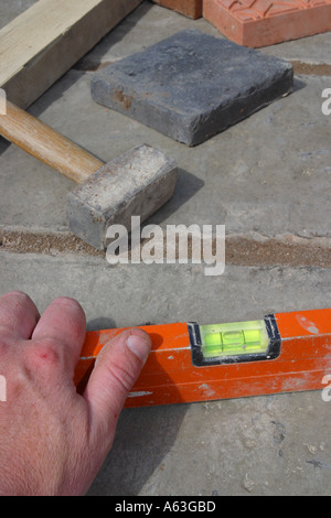 Gebäude eine Gartenterrasse mit Wasserwaage Werkzeug Platten und hand Stockfoto