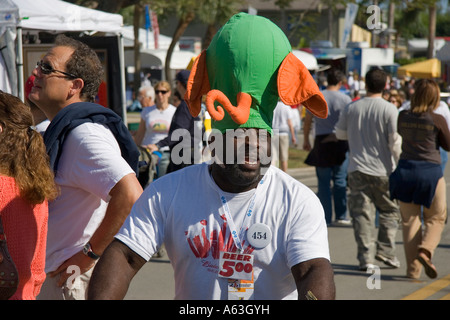 Afrikanische amerikanische Mann einen großen grünen und orangefarbenen Elefanten Hut Bier zu verkaufen. Coconut Grove Arts Festival in Miami, Florida Stockfoto