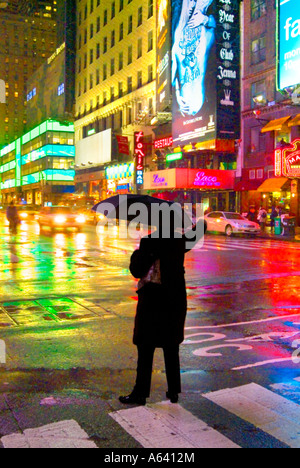 Mann hagelt Taxi mit Schirm im Regen in der Nacht, New York City Times Square, New York, USA Stockfoto