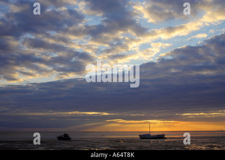 zwei einsame Boote im Meer am Snettisham beach, West Norfolk Küste mit herrlichen Sonnenuntergang hinter Stockfoto