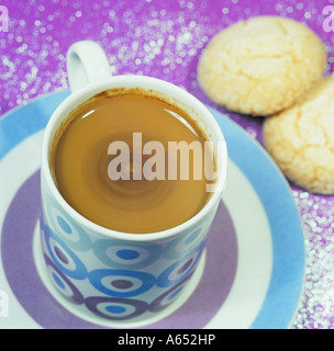 Eine Tasse Espresso-Kaffeemaschine mit einem wirbelnden Crema-Kopf. Zwei Amaretti im Hintergrund. Stockfoto