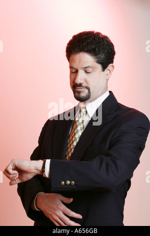 Mann gekleidet in Anzug mit einer sieht auf seine Uhr. Stockfoto