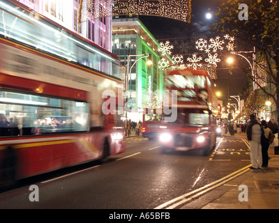 Busse bewegen sich unscharf, während sie unter den beleuchteten Dekorationen in Oxford Street West End London kurz vor Weihnachten in England Großbritannien fahren Stockfoto