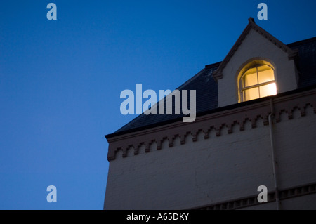 Beleuchtete Fenster im obersten Stockwerk des Gebäudes in der Nacht Stockfoto
