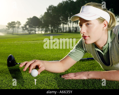 Jungen Golfspielerin liegen auf Platz, Ball am Abschlag zu platzieren Stockfoto