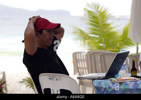 Philippinischen Mann aus Manilla an seinem Laptopcomputer arbeiten Urlaub in Boracay, Philippinen Stockfoto
