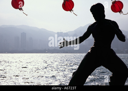 Eine Statue von Kultfigur Bruce Lee ist an der Hong Kong Uferpromenade The Avenue of Stars in Tsim Sha Tsui Silhouette. Stockfoto