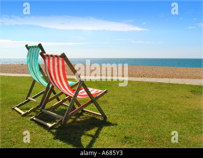 Leere gestreifte Liegestühle auf Rasen in der Nähe von Meer promenade Hastings Sussex England blauen Himmel flauschige Wolken Stockfoto