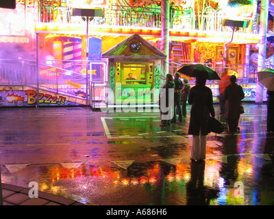 fairground ride with box office reflected in wet pavement Stockfoto