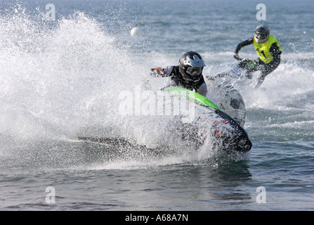 Zwei junge Männer oder Jugendliche, die in Richtung einer Markierungsboje auf einem kleinen Jetbike oder Jetski zu beschleunigen, während eines Rennens auf dem Meer oder Ozean Stockfoto