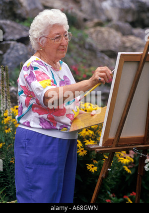 Ältere Frau malt in ihrem Garten Stockfoto