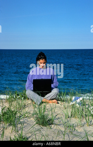Frau arbeitet an einem Laptop-Computer, während am Strand Stockfoto