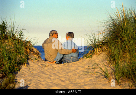 Älteres Paar genießen Sie Meer Sonnenuntergang während Sie gemütlich auf der Sanddüne Stockfoto