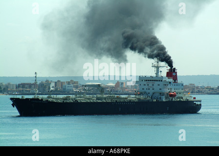 Seitenansicht Frachtschiff, das schwarzen Rauch und Rußemissionen vom Trichter aufstoßen, der die lokale Atmosphäre und Umwelt verschmutzt, Ankunft im Hafen von Palma Mallorca Spanien Stockfoto