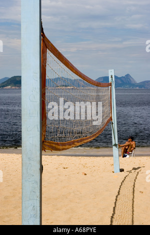 Mann sitzt auf einem Stuhl am Ende ein Volleyballnetz auf einem brasilianischen Strand in Rio De Janeiro Stockfoto