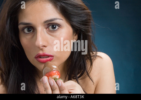 dunkle ethnische Frau schaut direkt in die Kamera hielt eine Schokolade überdachten Erdbeere Stockfoto