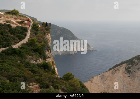 Touristen stehen auf [Klippe] Aussichtsplattform hoch über berühmte [Shipwreck Bay], [Smugglers Cove], Zakynthos, Zakynthos, Griechenland Stockfoto