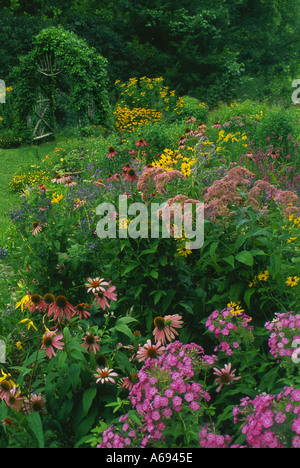 Handgemachte Garten Laube bedeckt Rebe mit Pfad der blühenden Sommer Wildblumen im Garten Stockfoto