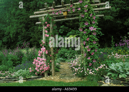 Schöne handgemachte rustikalen Zeder Arbor mit blühenden Rosen über eine Steinplatte Pfad in einem Blumengarten, Missouri Vereinigte Staaten von Amerika Stockfoto