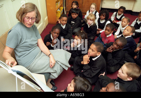 Weibliche Lehrer lesen zu einer Gruppe von Grundschulkindern Stockfoto