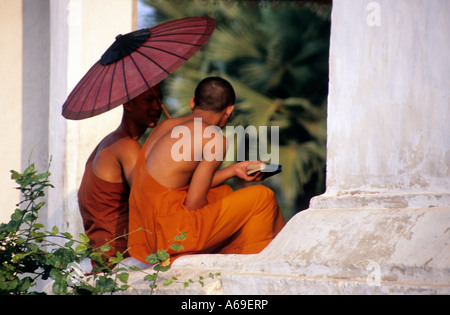 Zwei buddhistische Mönche sitzen auf einer Mauer eines Tempels in Luang Prabang.Laos. Stockfoto