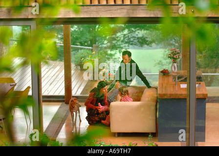 EINE JUNGE FAMILIE IN EIN MODERNES HAUS MIT GROßEN GLAS SCHIEBE-FENSTER UK Stockfoto