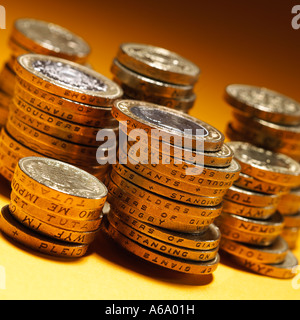 Englische Münzen - Pfund - gestapelt auf einem orangefarbenen Hintergrund Stockfoto