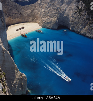 Shipwreck Bay mit fernen Figuren am Strand und man verlässt eine weiße Boote wake Westküste Zakynthos Insel der griechischen Inseln Stockfoto