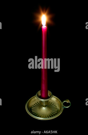 Rote Kerze in einer Messing-Halterung mit Leuchten von der Flamme Stockfoto