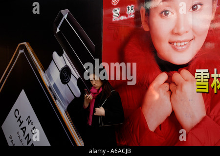 Eine Dame prüft Handy vor Plakatwand mit Paris Chanel No5 und eine chinesische Schauspielerin in Peking 25. Dezember 2005 Stockfoto