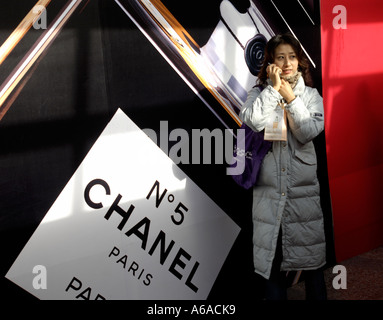 Eine Dame spricht mit Handy vor einem Plakat von Paris Chanel No. 5 Parfüm in Peking, China. 25. Dezember 2005 Stockfoto