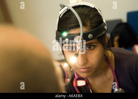 Eine asiatische Ärztin untersucht eine Patienten Kehle UK Stockfoto