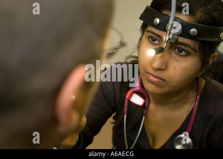 Eine asiatische Ärztin untersucht eine Patienten Kehle UK Stockfoto